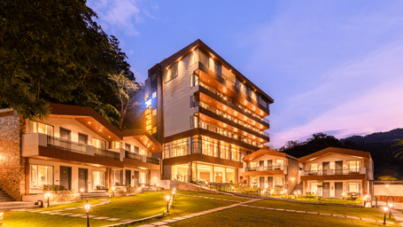 Exterior facade view of DLS Divine River Resort and Spa with warm lighting and garden area taken in the evening 